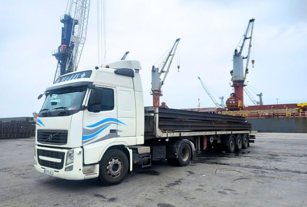 Camión de plataforma abierta de Transportes Zaldua cargando vigas de hierro desde el puerto